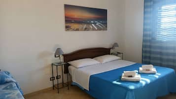 A hotel room with a bed, two bedside lamps, a painting on the wall, and a window with curtains.