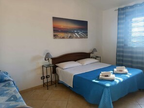 Una habitació d'hotel amb un llit, dues làmpades de nit, un quadre a la paret i una finestra amb cortines.