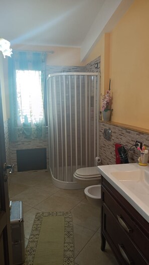 Une salle de bain avec une douche, des toilettes, un lavabo et un tapis à motifs.
