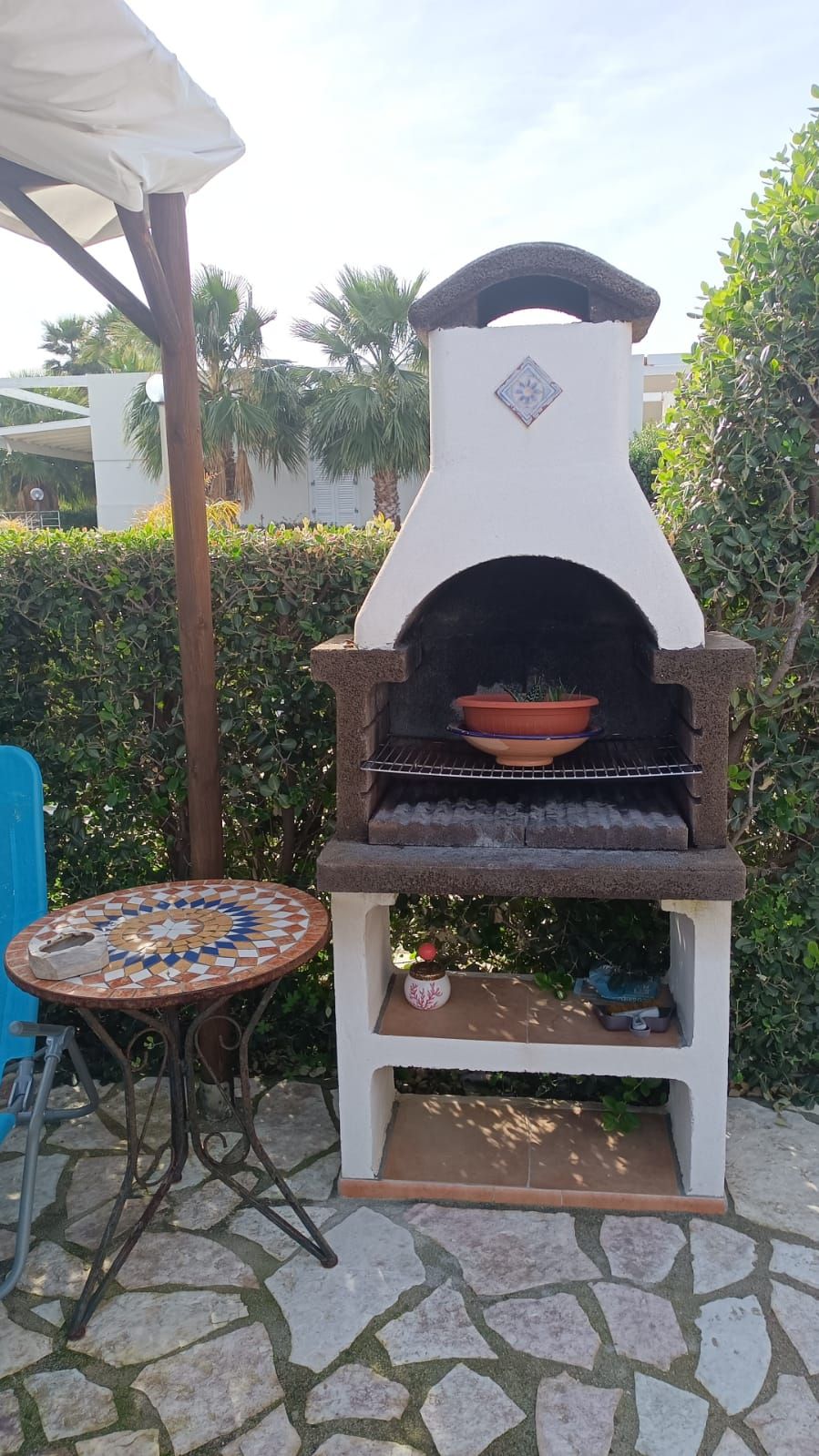 En utomhusgrill med en tegelugn, tillsammans med ett bord och stolar med kakelbeklädd yta i närheten.