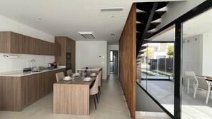 Une cuisine moderne avec un coin repas, des meubles en bois et une vue sur une terrasse extérieure, accessible par une porte vitrée.