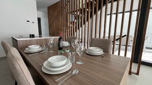 A modern dining area with a wooden table set for four, including plates, bowls, glasses, and cutlery. - 7LakesVilla - Santa Rosalia Lake Resort (Torre-Pacheco)