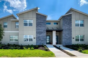 A modern two-story building with a symmetrical facade, large windows, and a central entrance. - Champions Gate 4BR w/ Pool + Themed Rooms (Kissimmee)