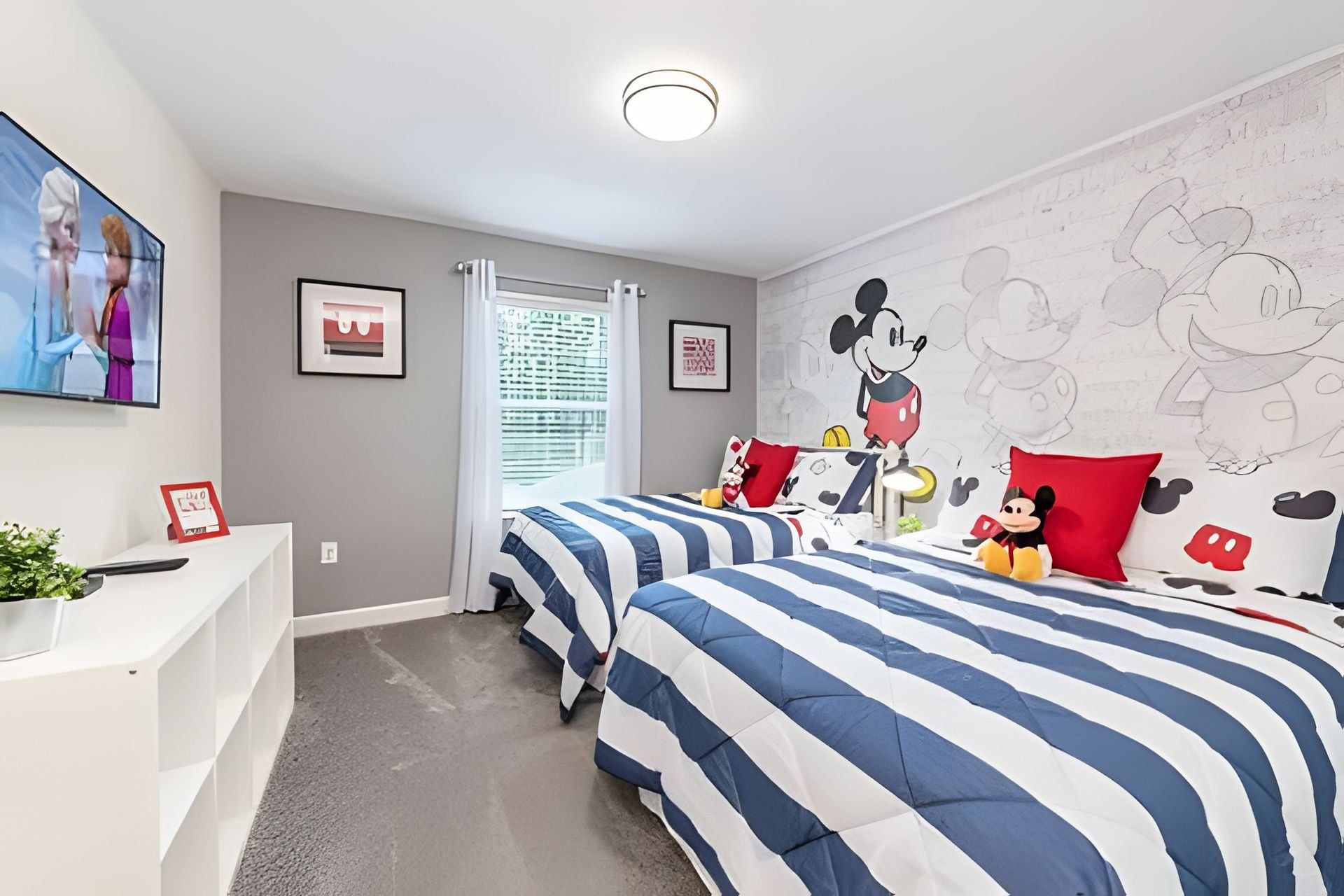 A bedroom with two beds, a desk, and a window with blinds.
