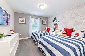 A bedroom with two beds, a desk, and a window with blinds. - Champions Gate 4BR w/ Pool + Themed Rooms (Kissimmee)