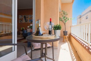 Ein Balkon mit Tisch, Topfpflanze und einer Weinflasche.