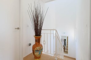 A staircase with a white railing, a door on the left, and a vase with branches on the floor. - Casa Sol - Mar Menor Golf (Torre-Pacheco)