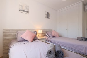 A bedroom with two beds, a nightstand with a lamp, and a wardrobe. - Casa Sol - Mar Menor Golf (Torre-Pacheco)