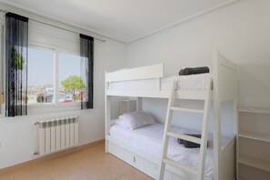 A bunk bed room with a window, radiator, and a view of houses outside. - Casa Sol - Mar Menor Golf (Torre-Pacheco)