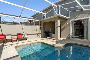 A swimming pool with a sunshade structure, a covered seating area, and a glass door leading to a room. - Disney-area 4BR Townhome w/ Heated Pool (Davenport)