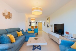 A modern living room with a sectional sofa, a coffee table, and a TV on a wooden cabinet. - La Casa Soleada - Mar Menor Golf Resort (Torre-Pacheco)