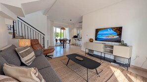 Ein modernes Wohnzimmer mit einer Couch, einem Couchtisch und einem Fernseher auf einem Schrank.