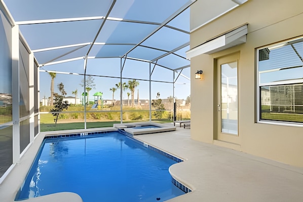 Una piscina con cerramiento de vidrio, una puerta y una ventana.