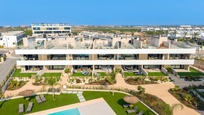 Ein modernes Mehrstöckhotel mit Außenpools, Liegestühlen und einem gepflegten Garten.