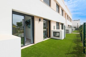 Ein modernes Wohngebäude mit großen Glasfenstern, einer flachen Dachkonstruktion und einem gepflegten Rasen.