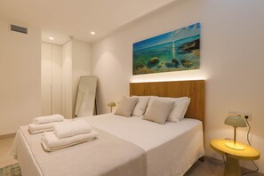 Ein Hotelzimmer mit einem Bett, einem Strandbild, einer Nachttischlampe und einem Spiegel.