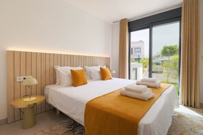 Ein modernes Hotelzimmer mit einem großen Bett, einem Nachttisch, einer Lampe und Blick ins Freie.