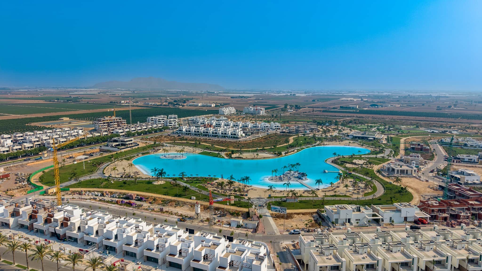 A residential area with modern architecture, a large central pool, and surrounding greenery.
