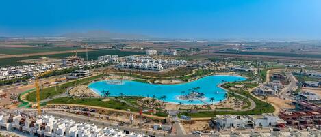 A residential area with modern architecture, a large central pool, and surrounding greenery.