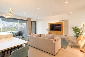 Ein modernes Wohnzimmer mit einer Couch, einem Esstisch, Stühlen, einem an der Wand befestigten Fernseher und einem Balkon mit Blick.