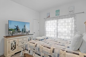 A bedroom with a bed, a dresser, a TV, and a window with blinds. - Championsgate 4BR w/ Pool, Themes, Near Disney (Davenport)