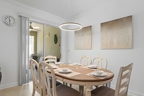Une salle à manger avec une table ronde, six chaises et un luminaire suspendu au design moderne.