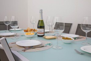 Ein Esstisch, gedeckt mit Tellern, Besteck, Gläsern und einer Weinflasche.
