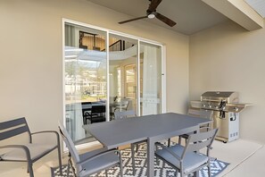 A dining area with a table and chairs, a ceiling fan, and a grill. - 5BR Home w/ Pool, Game Room + Near Disney (Davenport)