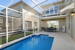 A modern house with a glass-enclosed patio, a swimming pool, and a barbecue area. - 5BR Home w/ Pool, Game Room + Near Disney (Davenport)