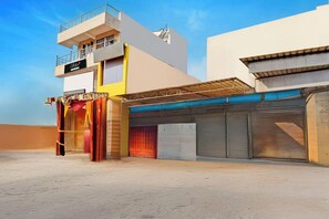 A multi-story building with a flat roof, a balcony on the upper floor, and a storefront with a closed shutter. - Collection O Meerut City Junction (Meerut)