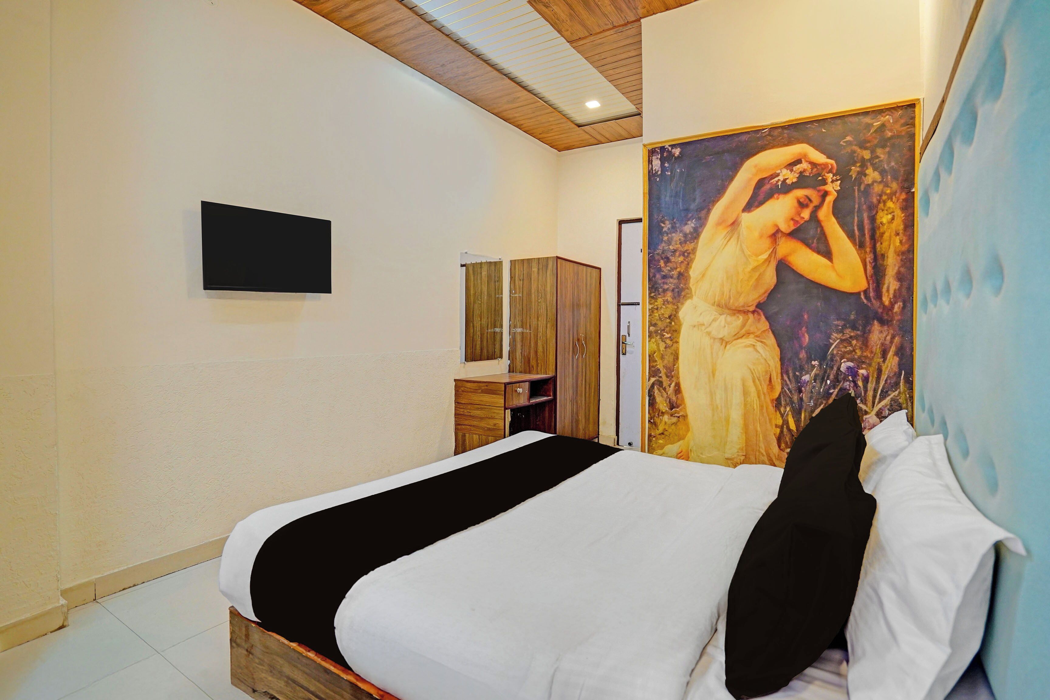 Un dormitorio con cama, un cuadro, un armario y un televisor en la pared.