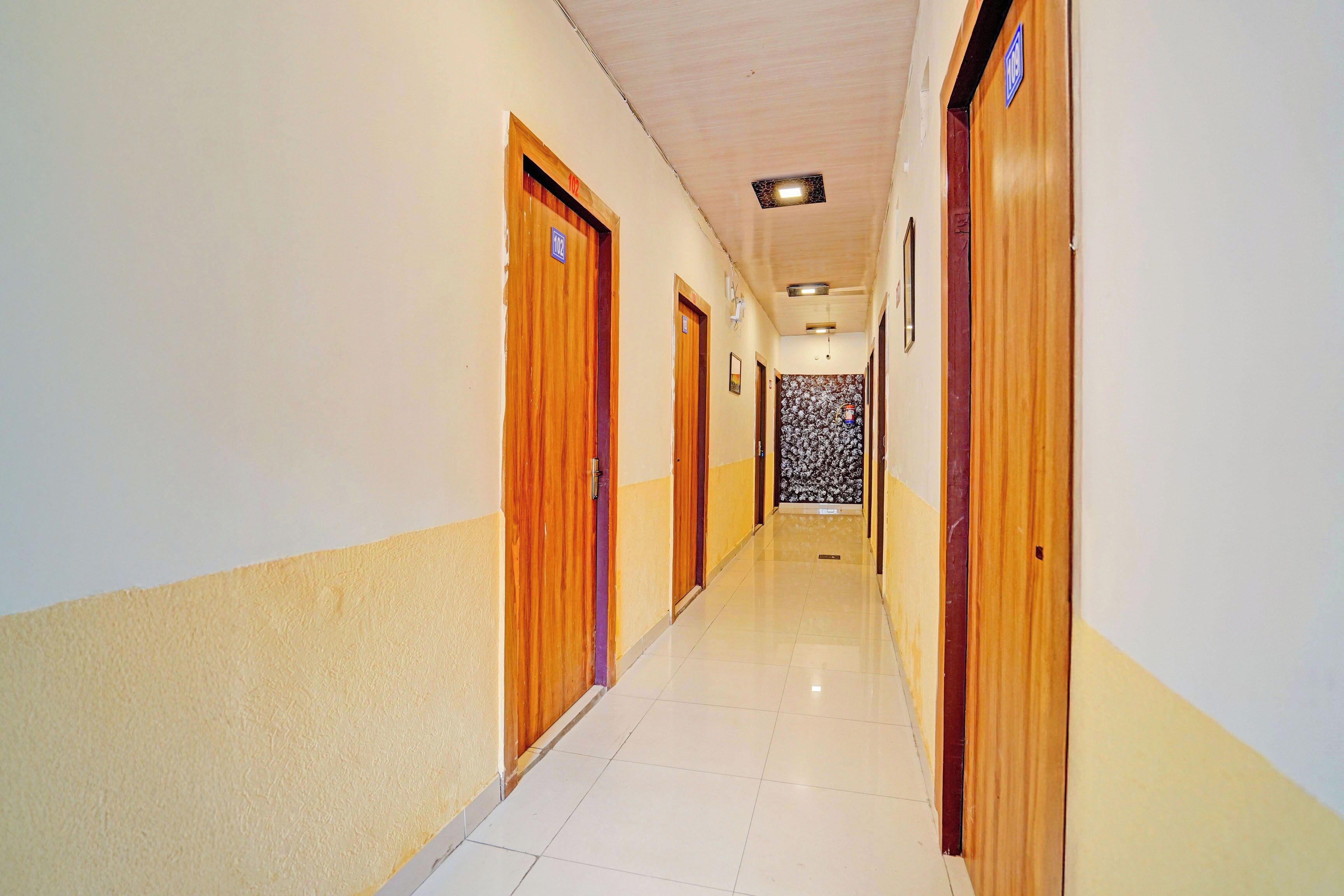 Un pasillo de hotel con puertas de madera, piso de baldosas e iluminación empotrada en el techo.