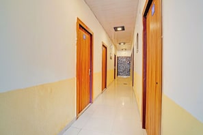 A hotel corridor with wooden doors, a tiled floor, and a ceiling with recessed lighting. - Collection O Meerut City Junction (Meerut)