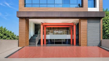A modern building with a red entrance, a staircase, and a garage door.