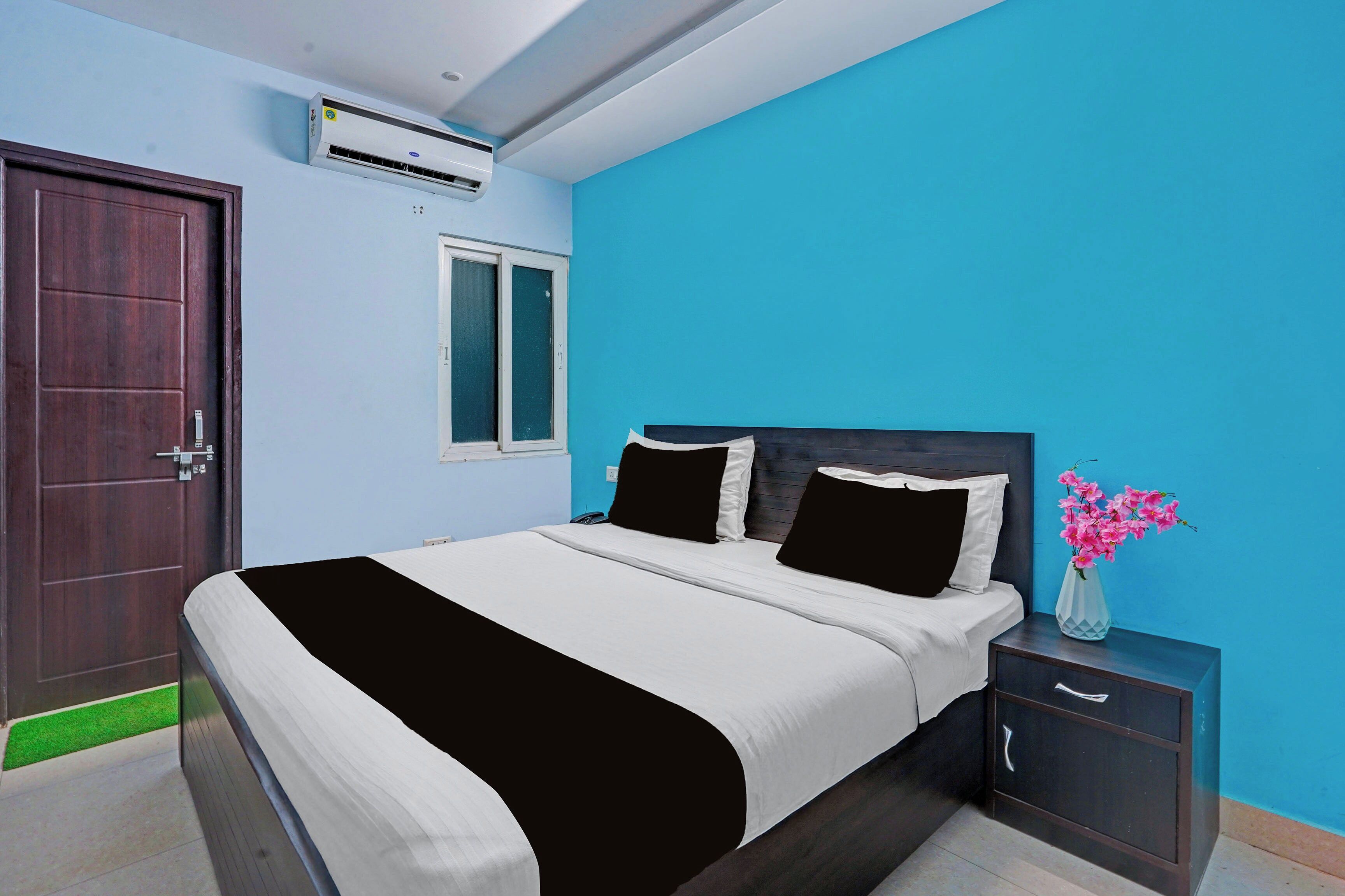 A bedroom with a bed, bedside table, and a vase with flowers.