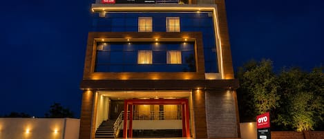 A modern hotel with a two-story structure, a prominent entrance with a red frame, and a sign indicating the availability of rooms on the app.