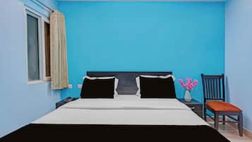 A room with a bed, a chair, a nightstand, a vase with flowers, and a window with curtains.