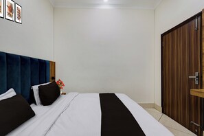 Una habitación de hotel con una cama, un armario de madera y una pared decorada con cuadros.
