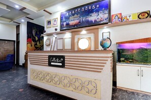 Un mostrador de recepción con un letrero que indica zona de servicio de empresa, un televisor montado arriba y un acuario a la derecha.