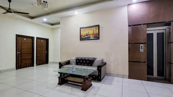 Una habitación con una mesa de centro de vidrio, un sofá, un ventilador de techo y un cuadro en la pared.