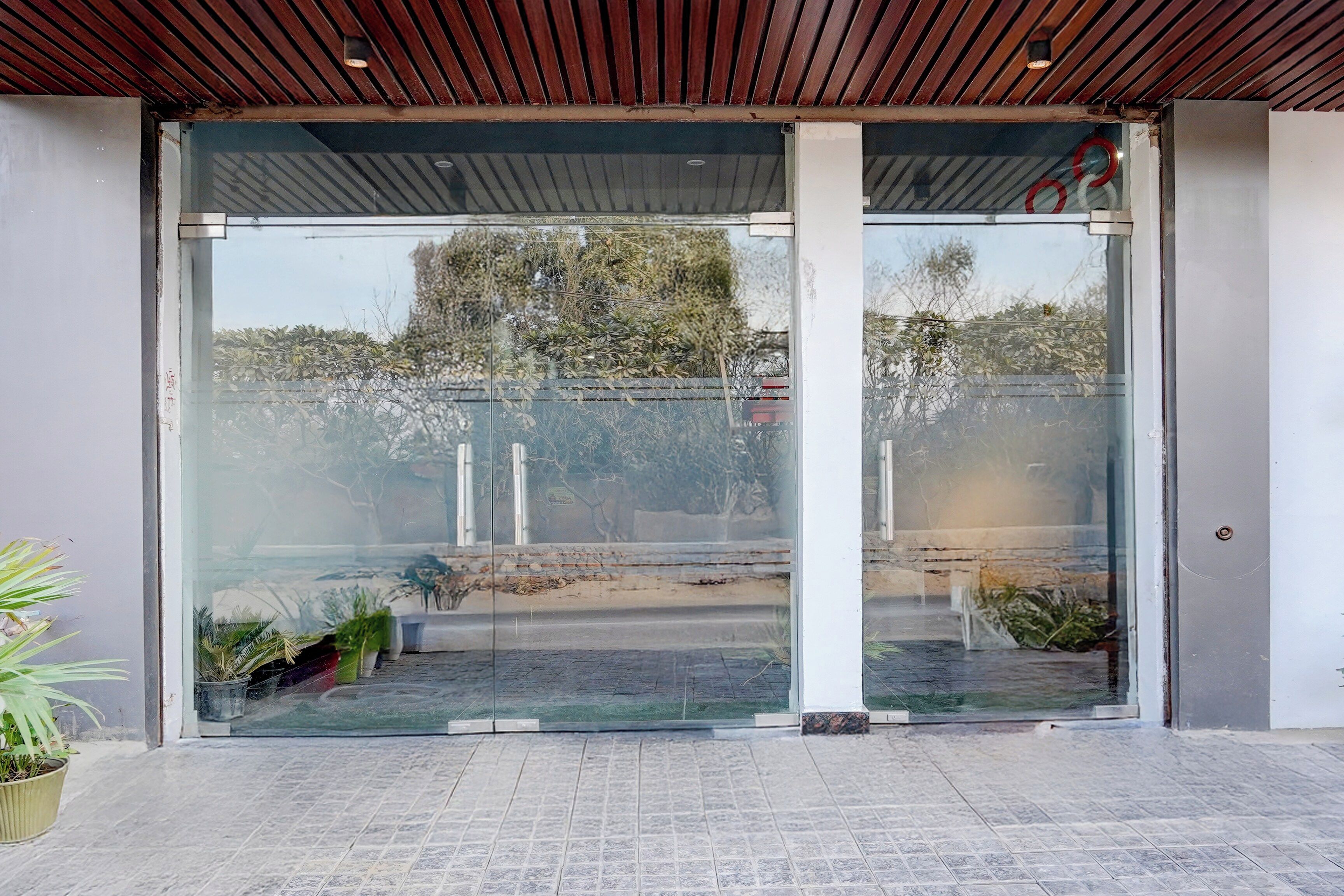 A building entrance with a glass door, a tiled floor, and a metal roof.