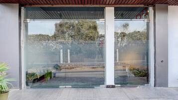 A building entrance with a glass door, a tiled floor, and a metal roof.