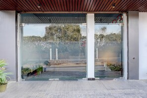 Una entrada de edificio con puerta de cristal, piso de baldosas y techo de metal.