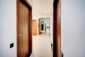 Un pasillo con puertas de madera, un extintor y una planta en maceta.
