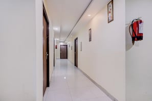 A hotel corridor with doors, a fire extinguisher, and a framed picture on the wall.
