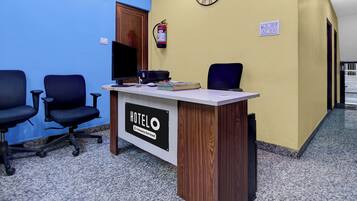 Un comptoir de réception d’hôtel avec une horloge, un extincteur et un panneau indiquant qu’il est entretenu par l’entreprise.