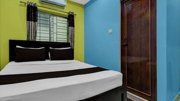 Un dormitorio con cama, cortinas, una ventana, un equipo de aire acondicionado y una puerta de madera.