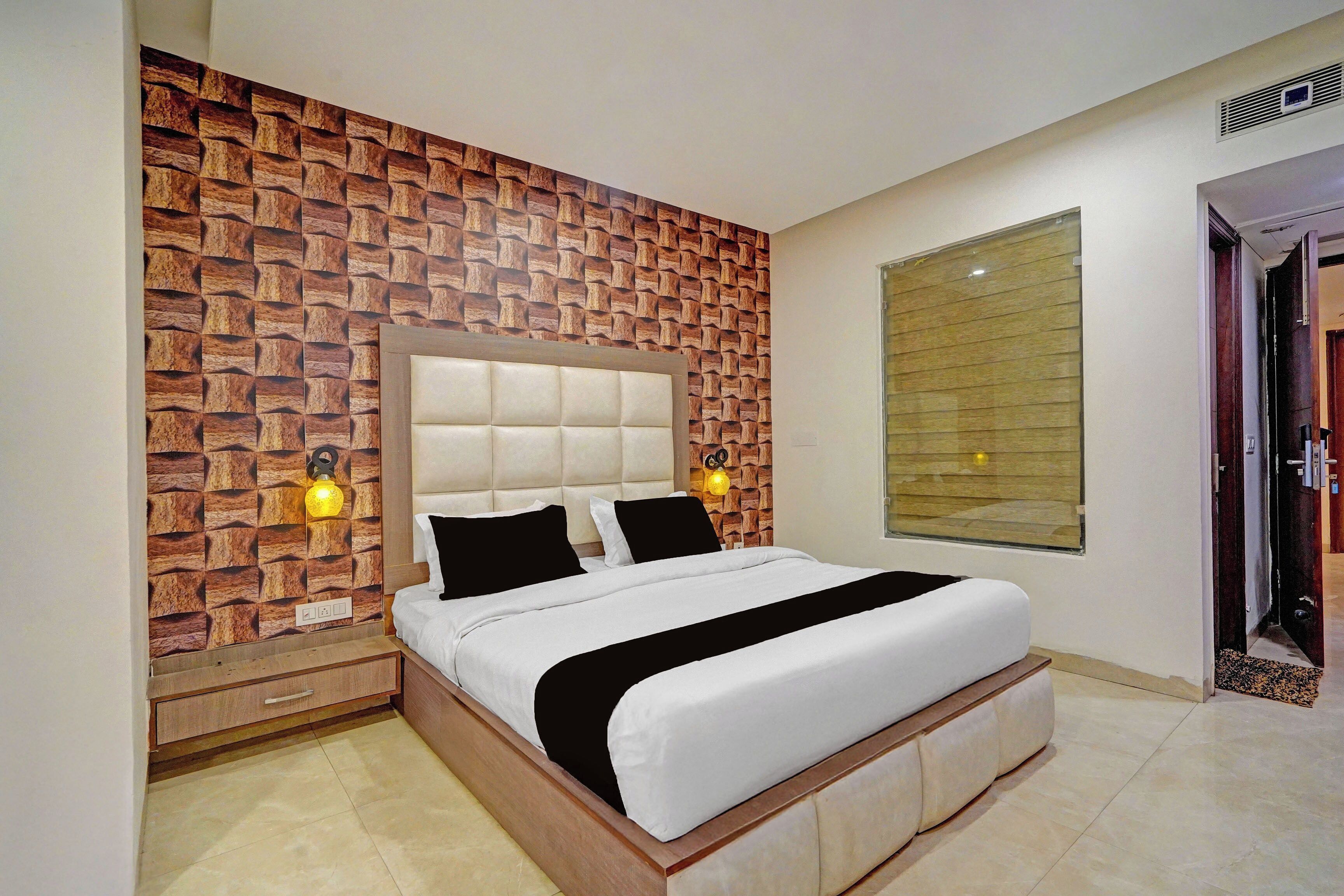 A bedroom with a bed, a wall with a brick pattern, a window, and a door.