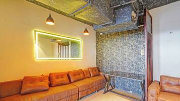 A modern interior with a sectional sofa, a mirror, and a patterned wall.