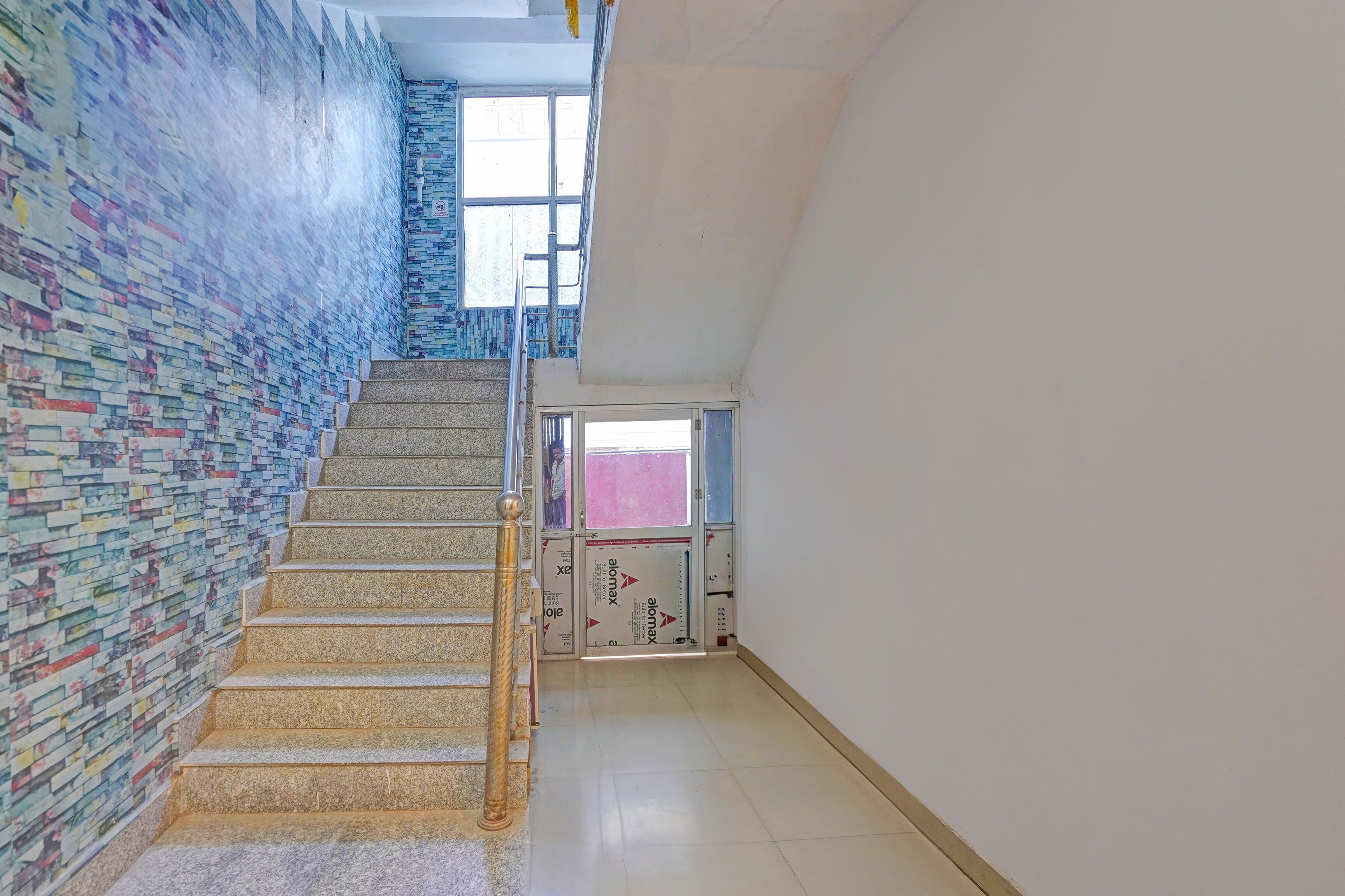 Una escalera con un muro estampado, una barandilla de metal y una ventana en la parte superior.